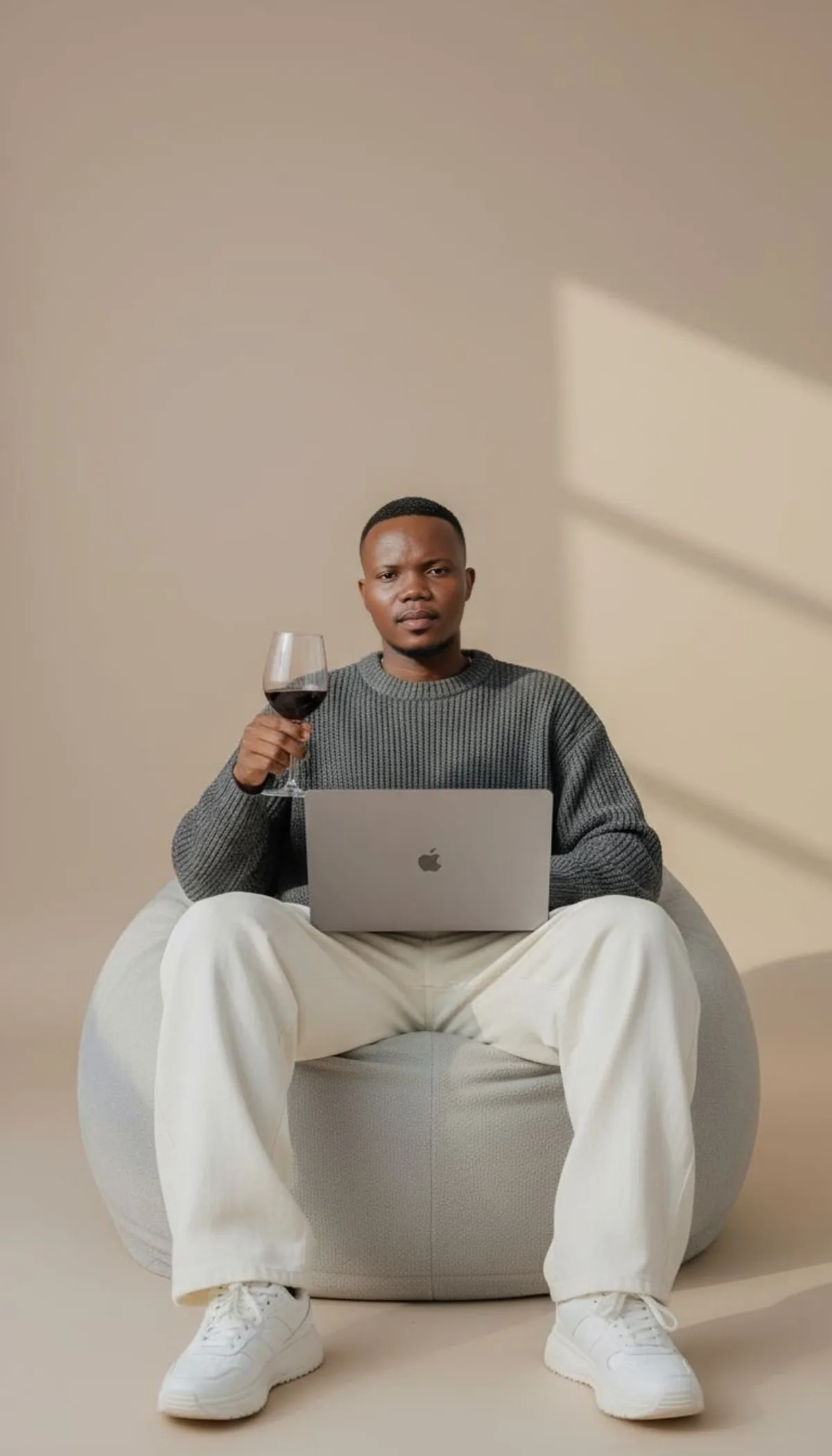 男模特坐懒人沙发，手持红酒与MacBook