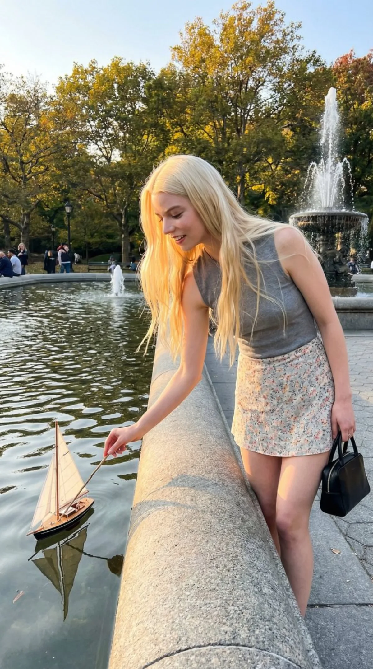 精修视角下的年轻女子与公园喷泉中的帆船互动